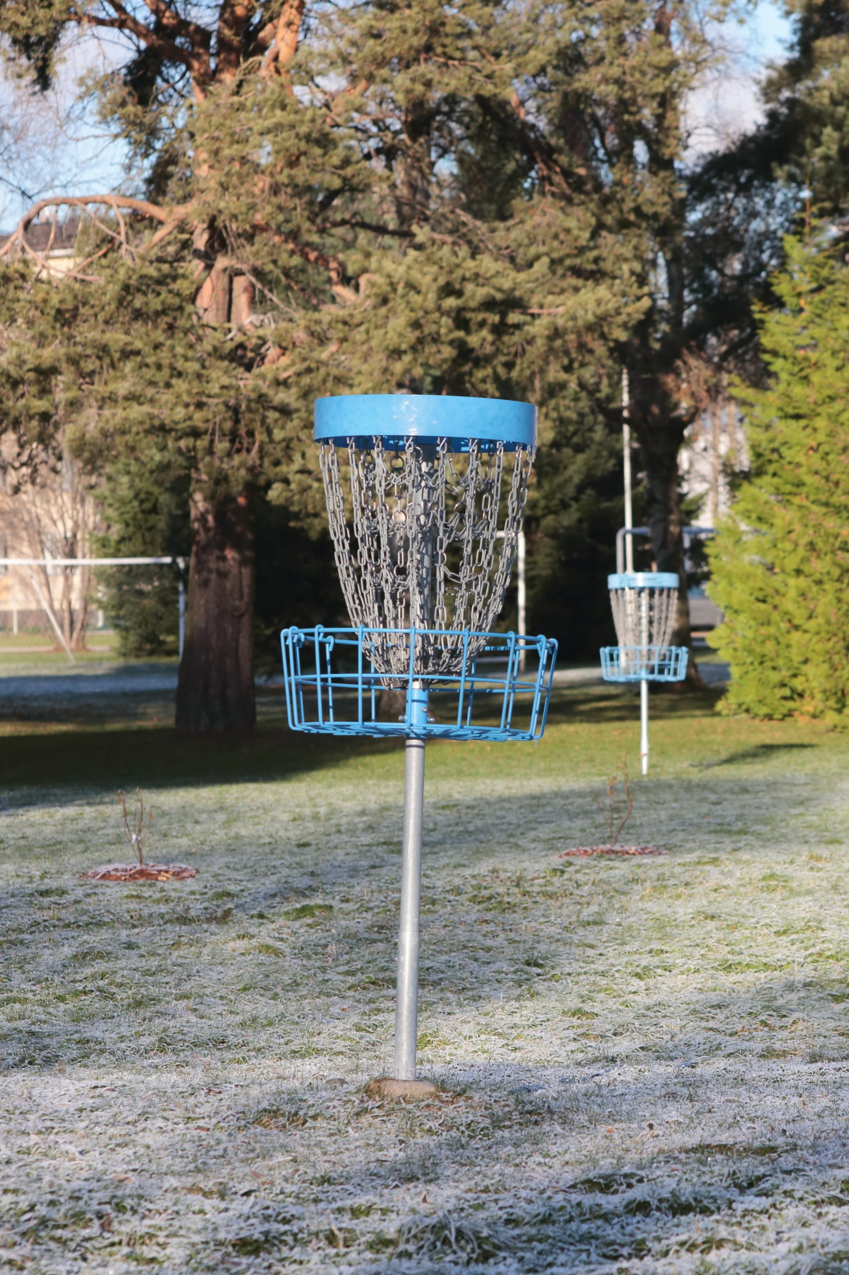 Disc golf basket standing in a green park
